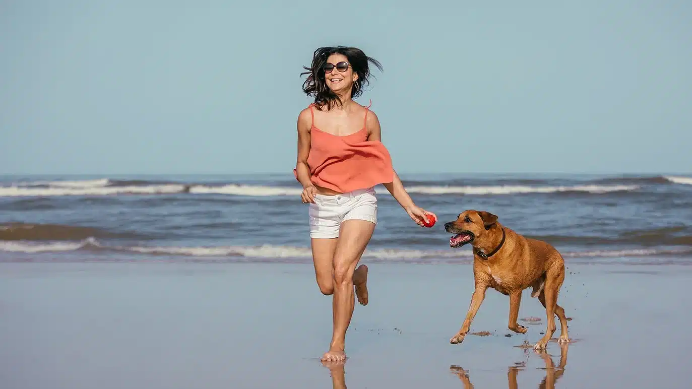 Happy lady and her dog at the beach